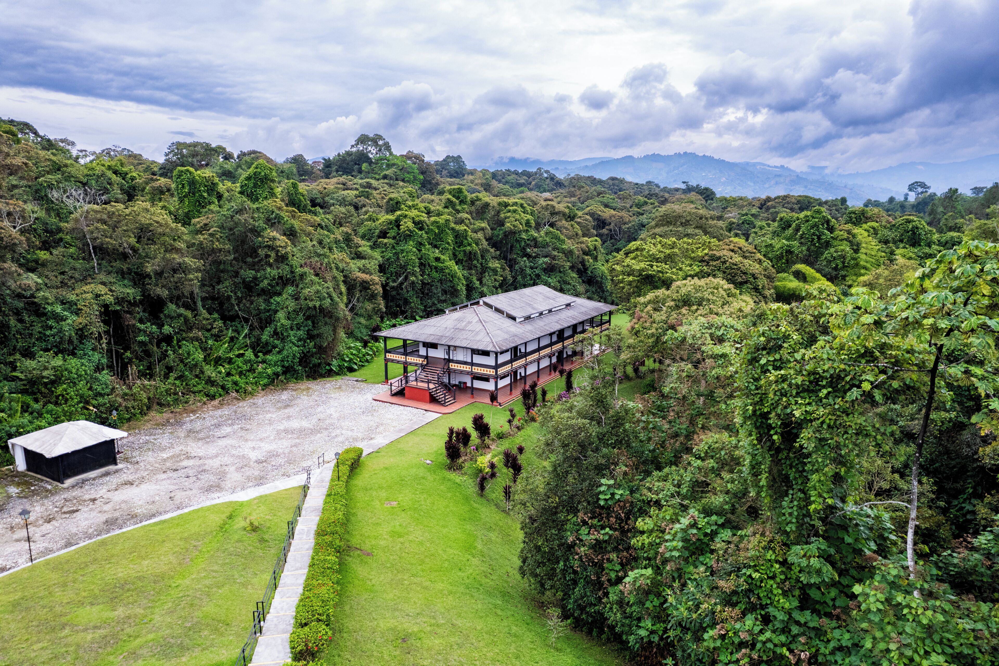 A modern building with a flat roof, surrounded by lush greenery and a clear sky.