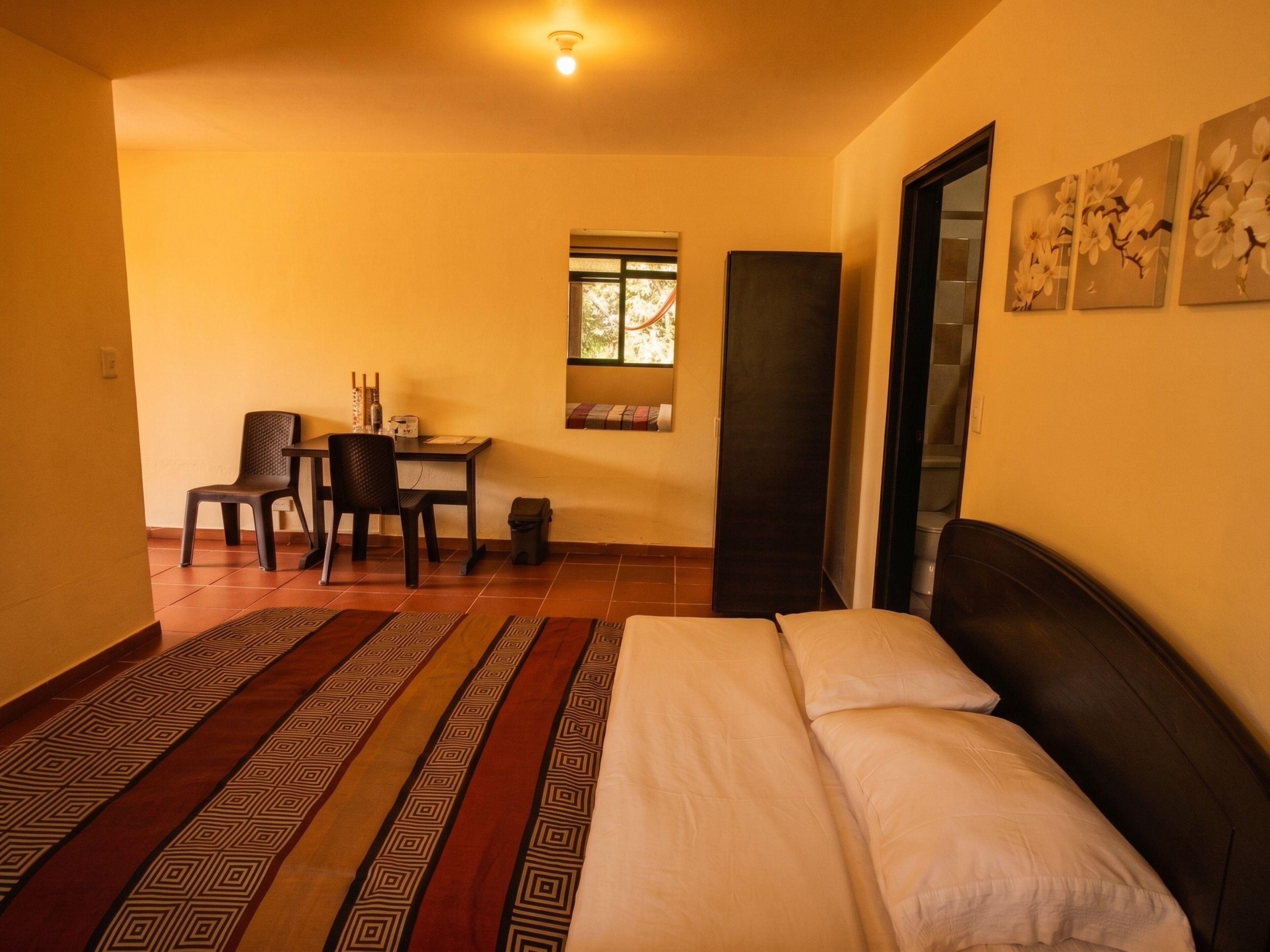 Una habitación con cama, escritorio, silla, ventana y puerta.