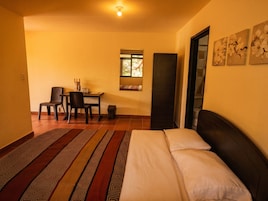 Una habitación con cama, escritorio, silla, ventana y puerta.