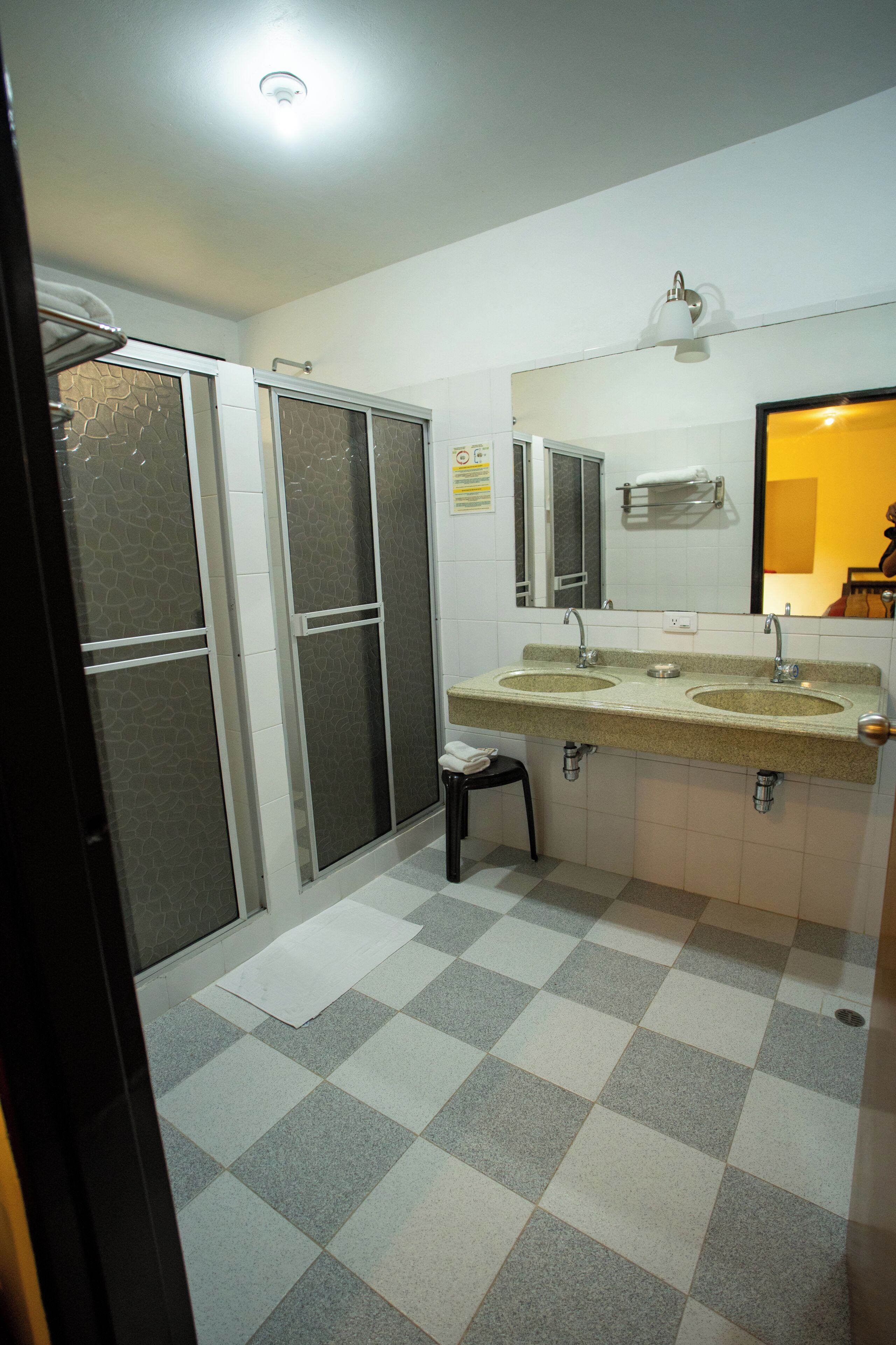 Une salle de bain avec deux lavabos, un miroir et un espace douche.