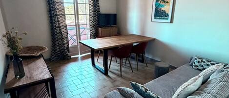Una stanza con un tavolo di legno, un divano, una TV e un quadro appeso al muro.