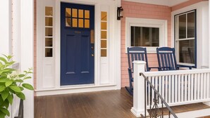 Une maison avec une porte bleue, une balustrade blanche et un mur en briques.