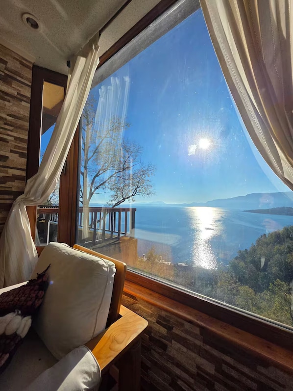 A room with a large window, a wooden bench, and a white cushioned seat.