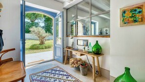Une pièce avec un bureau en bois, une chaise, une grande fenêtre et une porte donnant sur l’extérieur.