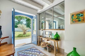 A room with a wooden desk, a chair, a large window, and a door leading outside.