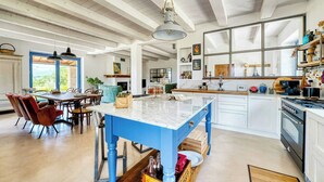 Une cuisine spacieuse avec un îlot central bleu, des armoires blanches et une grande fenêtre.