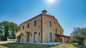 Un bâtiment en pierre avec un toit en pente, de nombreuses fenêtres et une pelouse bien entretenue.