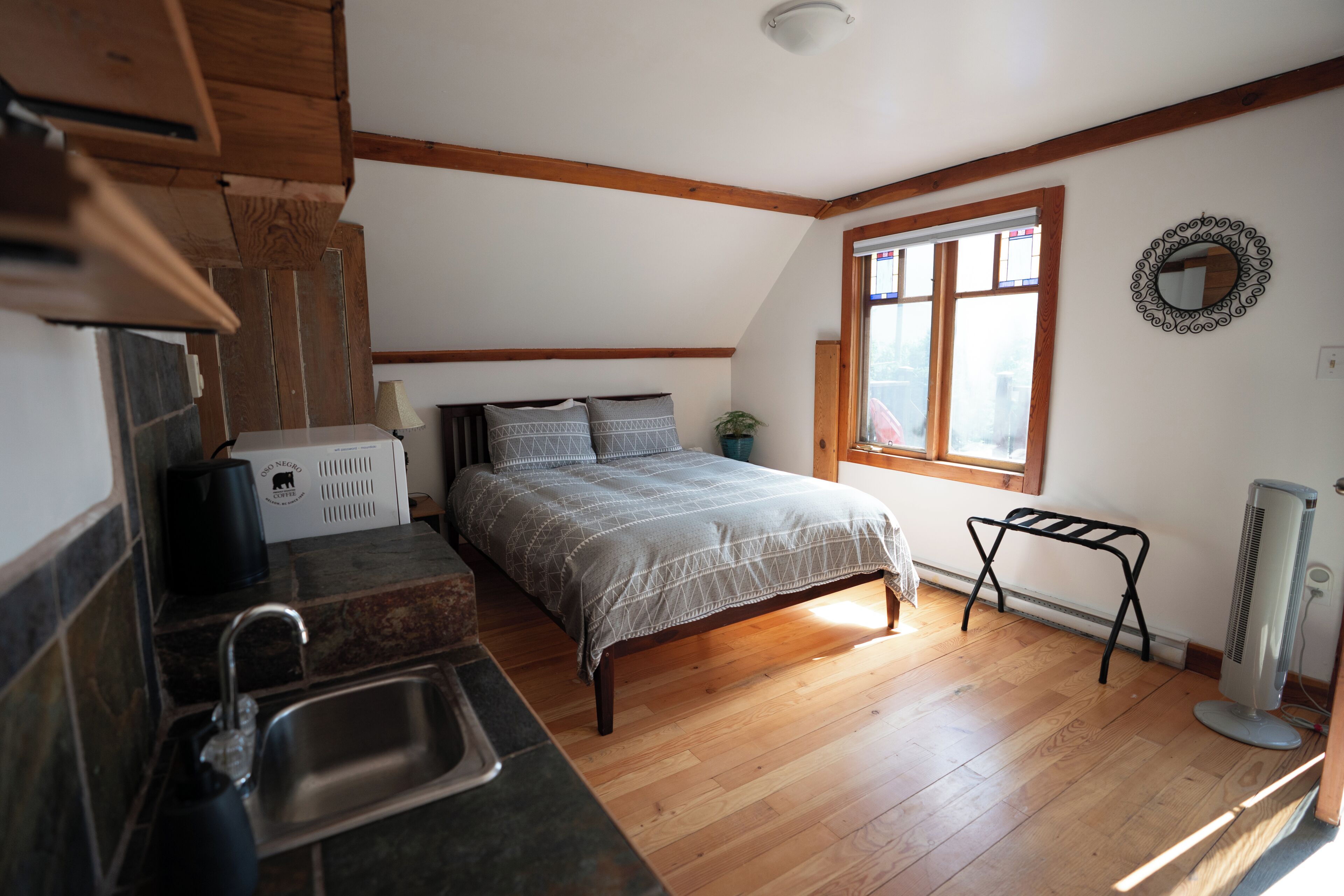 A bedroom with a bed, a window, a radiator, and a small table.