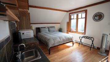 A bedroom with a bed, a window, a radiator, and a small table.