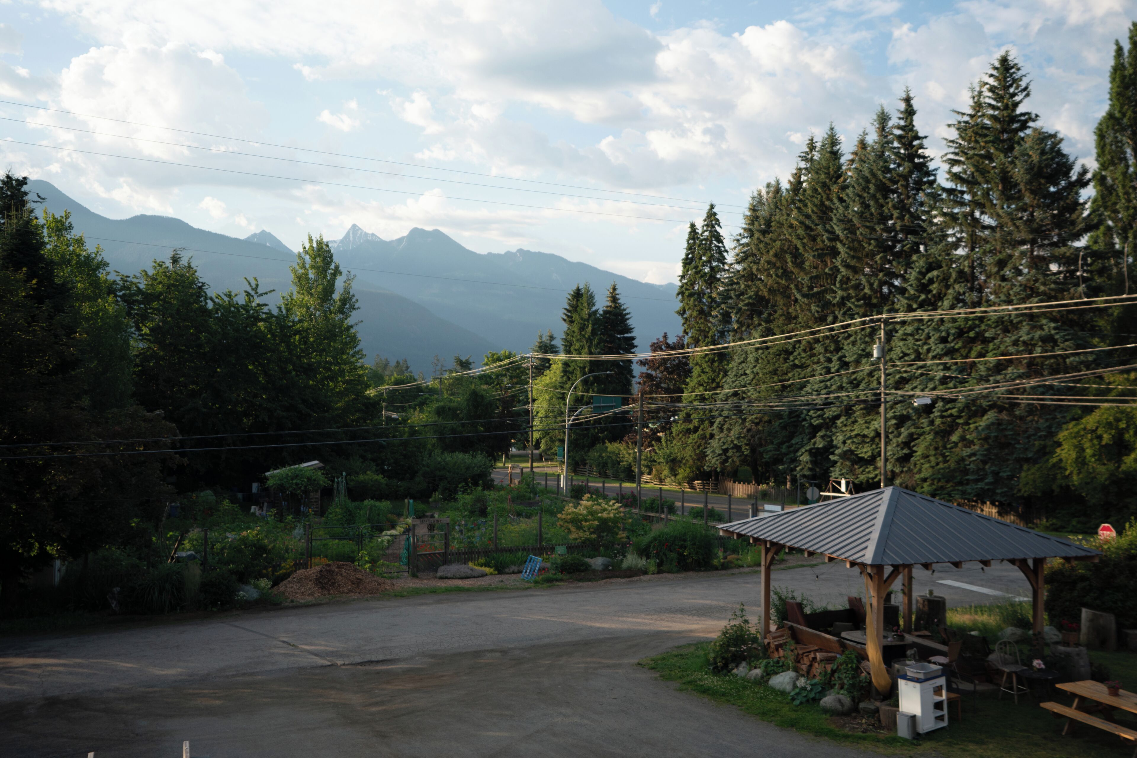 A rural setting with a gazebo, a paved area, and a mountain backdrop.