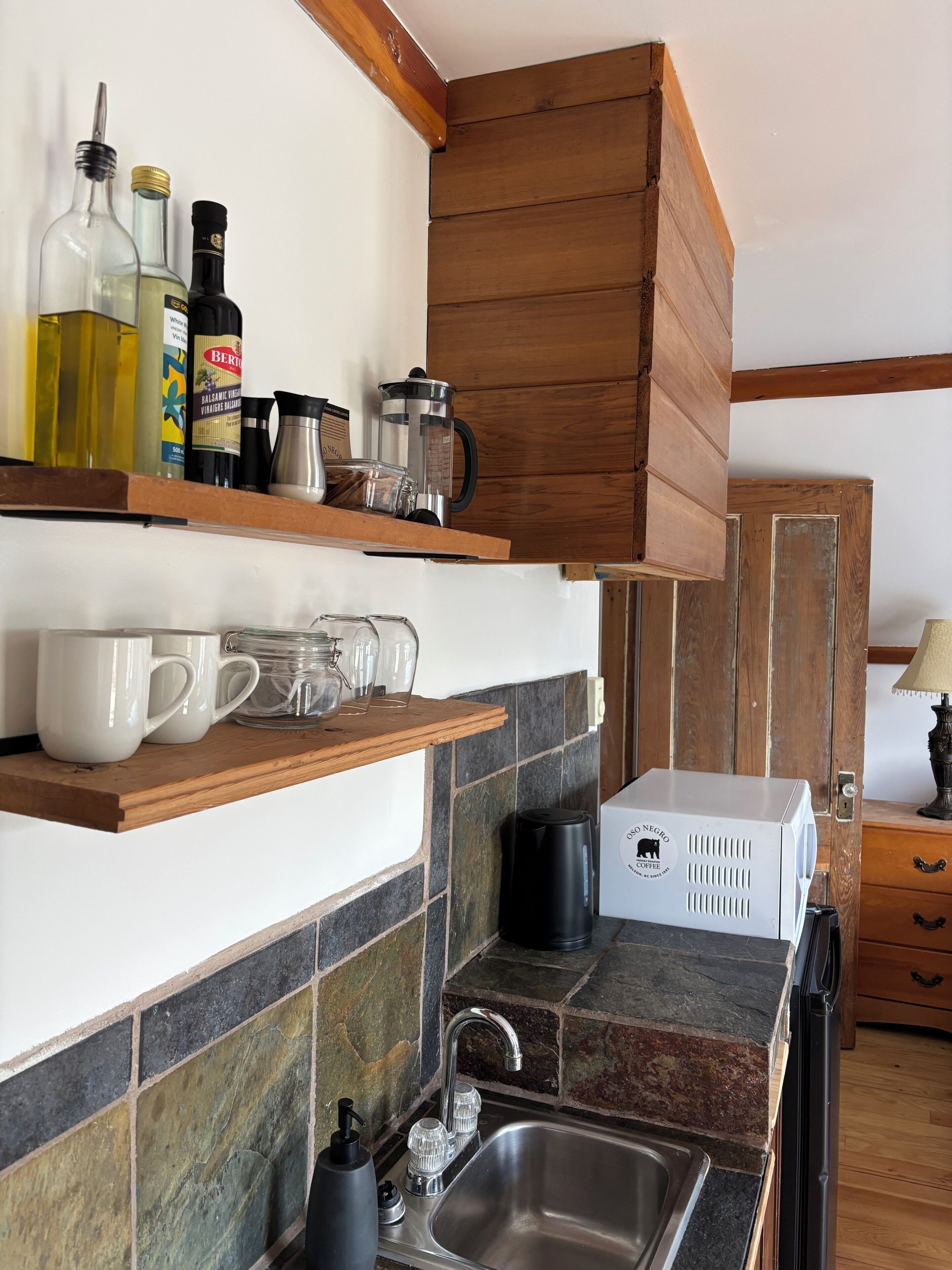 A kitchen with wooden cabinets, a coffee maker, and various kitchen items on shelves.