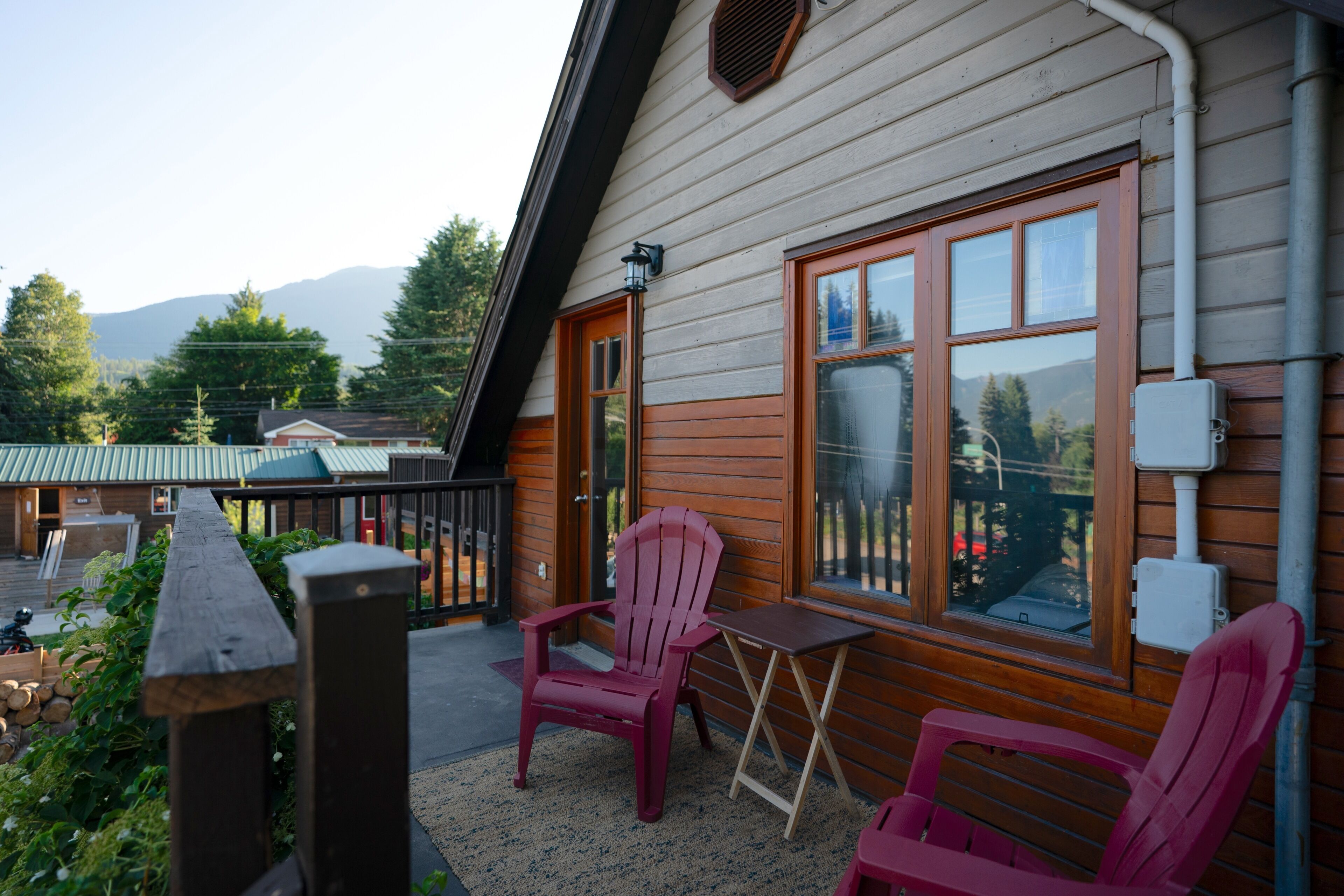 Une cabane en bois dotée d’un balcon, de deux chaises et d’une table.