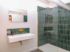 A bathroom with a white sink, a mirror, and a glass-enclosed shower area. - Reddaway Byre (Okehampton)