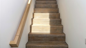 Un escalier en bois, doté d’une rampe, menant à un palier.