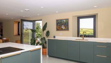 A modern kitchen with a large island, a dining area with a table and chairs, and a large window with a view of the countryside.