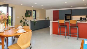 Une cuisine moderne avec un coin repas, une grande fenêtre et une vue sur la verdure.