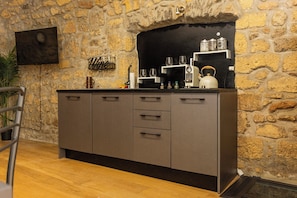 Cuina amb paret de pedra, televisió de pantalla plana i cafetera.