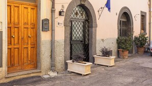 Un bâtiment doté d’une porte à double battant en bois, d’un portail noir et de deux plantes en pot.