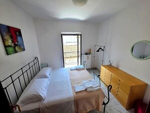 A bedroom with a bed, a dresser, a window, and a painting.