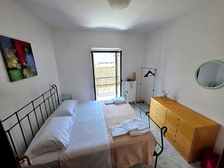 A bedroom with a bed, a dresser, a window, and a painting.