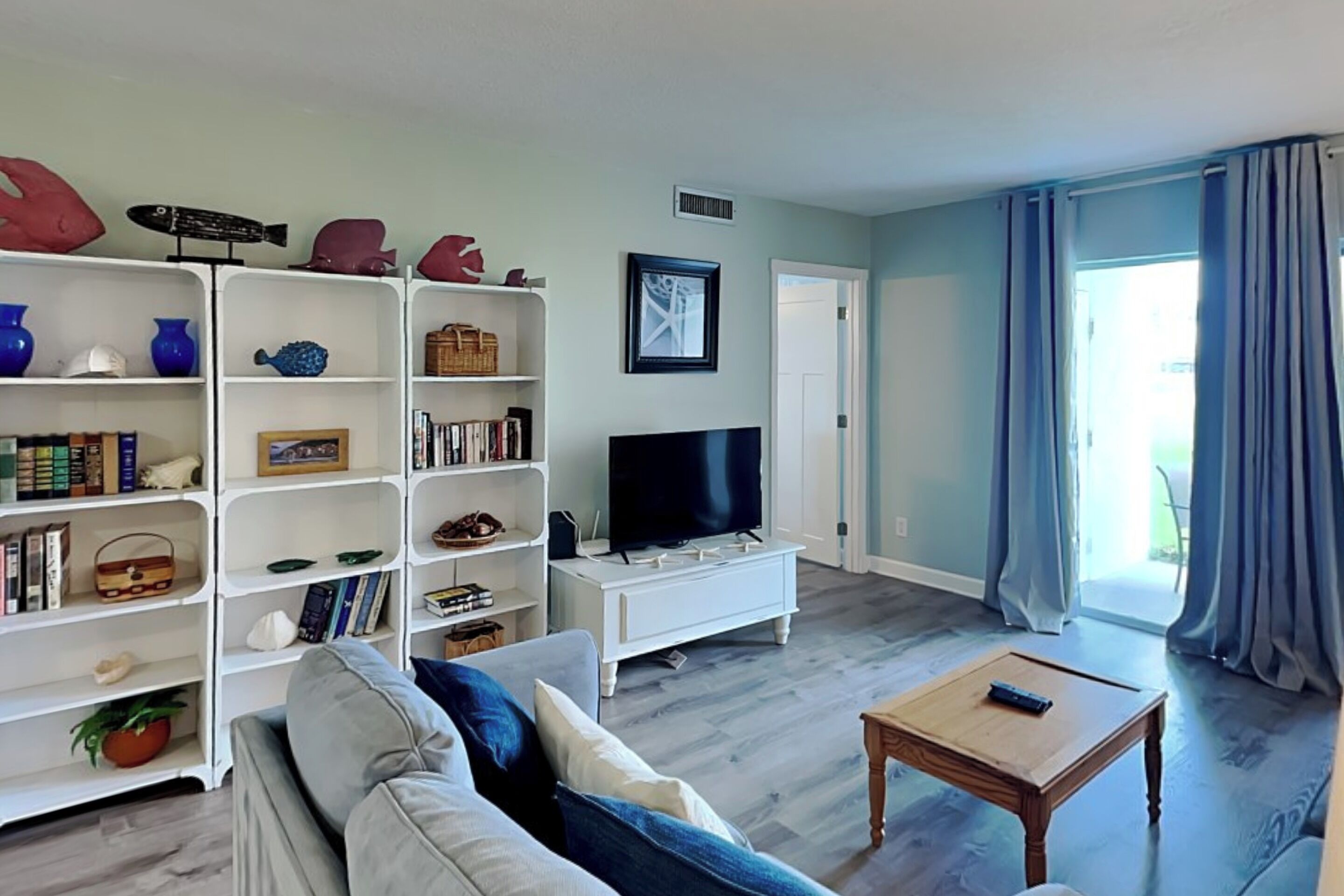 A living room with a sofa, TV, bookshelf, and a window with curtains.