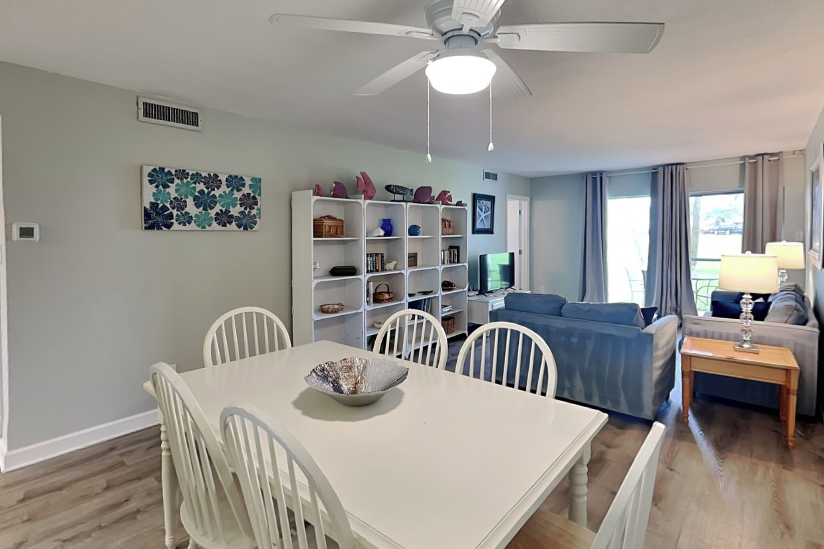 Un salon comprenant une table à manger, des chaises, un canapé, un téléviseur et un ventilateur de plafond.