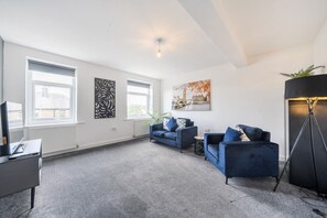 Ein modernes Wohnzimmer mit einer Sofagarnitur, einer Stehlampe und Kunstwerken an den Wänden.