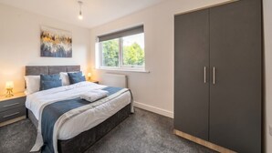 A bedroom with a bed, bedside tables, a window, and a wardrobe. - 2-Bed Flat in Newsome · Sleeps 4 · Gated Parking near Castle Hill (Newsome)