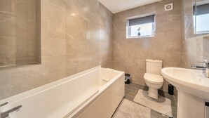 A modern bathroom with a bathtub, toilet, and sink. - 2-Bed Flat in Newsome · Sleeps 4 · Gated Parking near Castle Hill (Newsome)