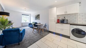 A modern kitchen with white cabinets, a built-in microwave, and a washing machine. - 2-Bed Flat in Newsome · Sleeps 4 · Gated Parking near Castle Hill (Newsome)
