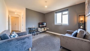 Una sala de estar con dos sofás, un mueble para televisión y un comedor.