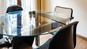 A modern dining area with a glass table, black chairs, a woven pendant light, and a cityscape painting on the wall. - Central, bright, and quiet (Madrid)