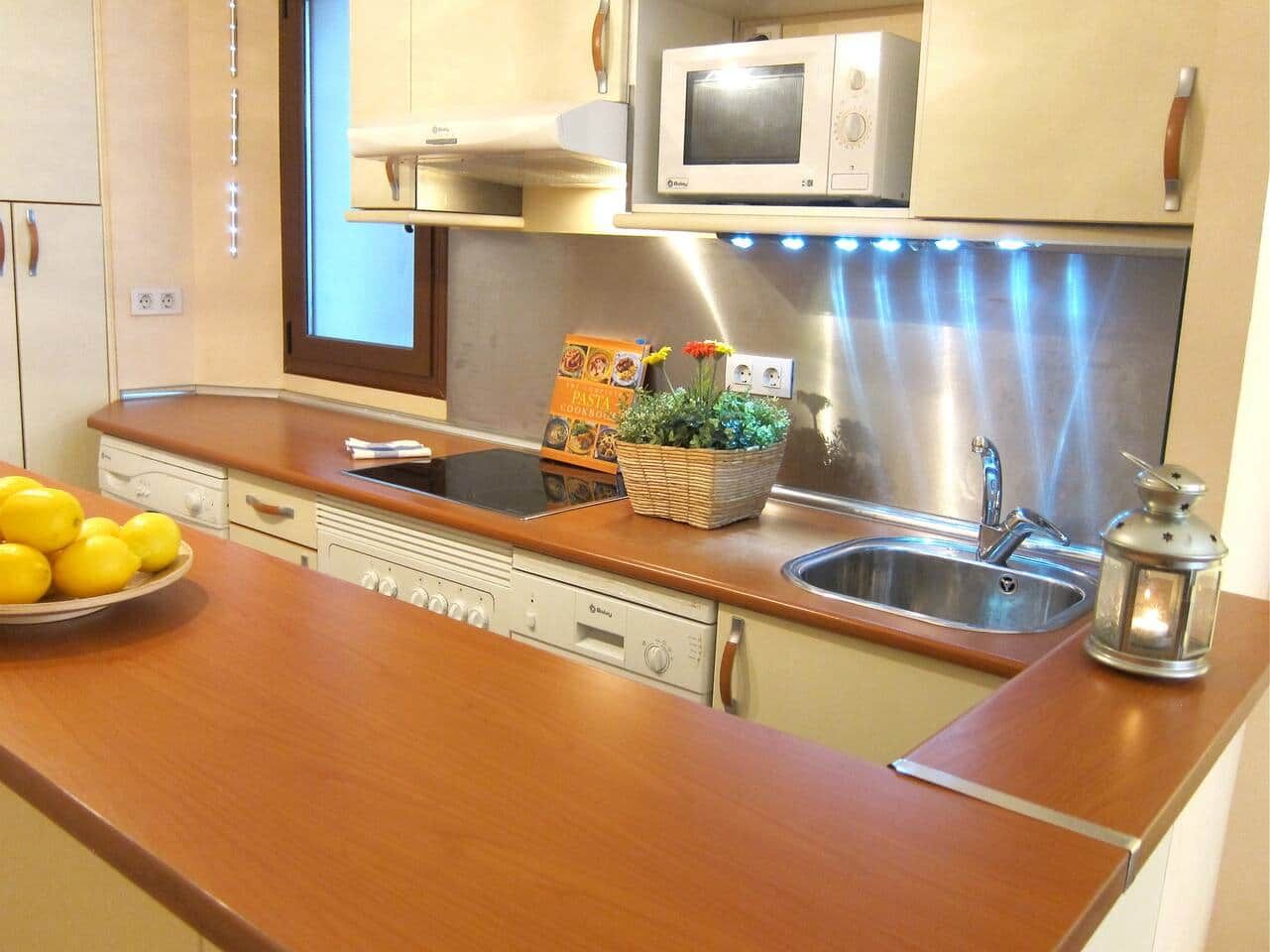 Eine moderne Küche mit Edelstahlgeräten, einer Holz Arbeitsplatte und einem eingebauten Geschirrspüler.