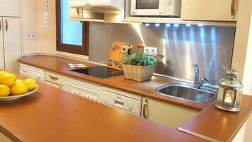 Una cocina moderna con electrodomésticos de acero inoxidable, encimera de madera y lavavajillas integrado.