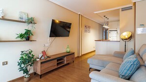 A living room with a TV, wooden entertainment unit, sofa, and potted plants. - Central, bright, and quiet (Madrid)