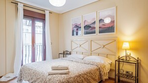 Ein Schlafzimmer mit einem Bett, einem Nachttisch, einer Lampe und einem Fenster mit Vorhängen.