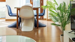 Ein modernes Wohnzimmer mit Essbereich, Fernseher und einer Topfpflanze.