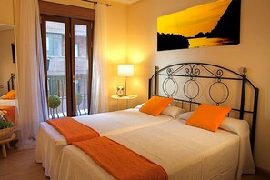 Ein Hotelzimmer mit zwei Betten, einem Balkon, einem Gemälde und einer Lampe.