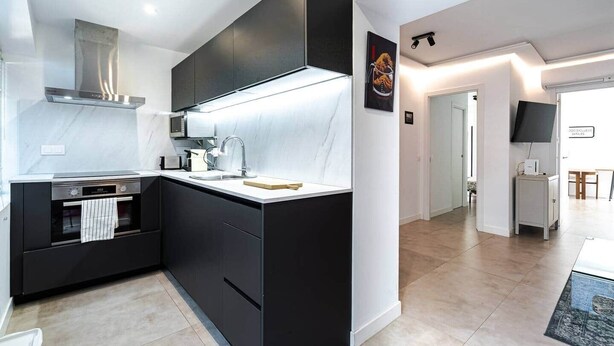 A modern kitchen with a built-in oven, microwave, and stainless steel range hood. - Comfortable, quiet, newly renovated (Madrid)