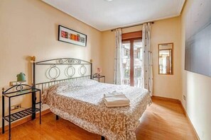 Una camera da letto con un letto, un comodino, una finestra con tende e una porta.