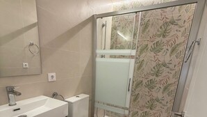 Une salle de bain moderne avec une douche à parois de verre, un lavabo blanc et des toilettes.