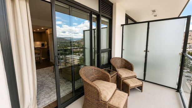 Un balcon doté de meubles en osier et d’une porte vitrée donnant sur un coin cuisine.