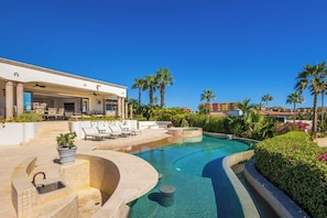 A pool area with lounge chairs, a pergola, and a building with a white facade. - Live the Cabo Dream, Luxurious 5-bedroom Oceanfront Paradise in Cabo San Lucas (Cabo san lucas)
