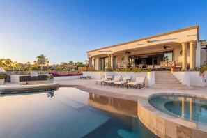 Ein modernes Haus mit Swimmingpool, Sitzgelegenheiten im Freien und einer überdachten Terrasse.