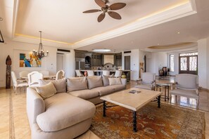 A spacious living room with a large sectional sofa, a coffee table, and a dining area with chairs. - Live the Cabo Dream, Luxurious 5-bedroom Oceanfront Paradise in Cabo San Lucas (Cabo san lucas)