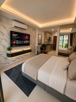 Ein modernes Schlafzimmer mit einem großen Bett, einem an der Wand montierten Fernseher, einer Küchenzeile und einem Balkon mit Blick.