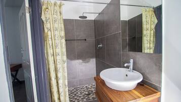 A bathroom with a shower, a sink, and a mirror.