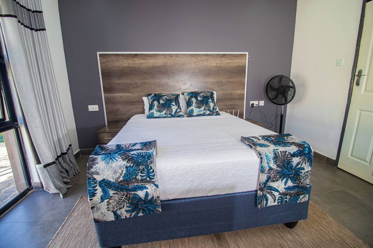 A bed with a wooden headboard, a white mattress, and blue floral bedding.
