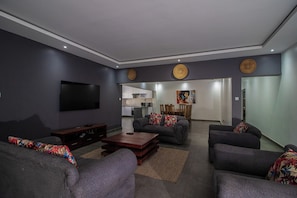 Una sala de estar moderna con sofás grises, un televisor de pantalla plana y una mesa de centro de madera.