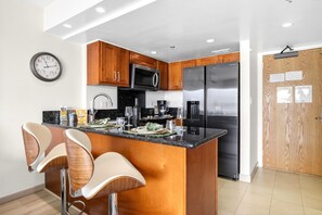Una cucina moderna con mobili in legno, elettrodomestici in acciaio inossidabile e un'isola centrale con sgabelli da bar.